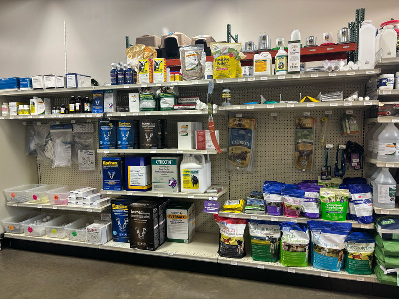 Store shelves filled with various agricultural products, including animal feed bags, supplements, and veterinary supplies. The aisle is organized and well-stocked.