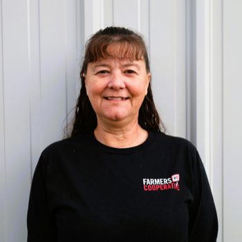 Person wearing a black sweatshirt with 'Farmers Cooperative' logo against a white wall